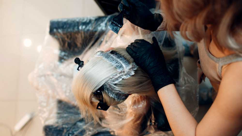 stylist applying hair dye to client's roots