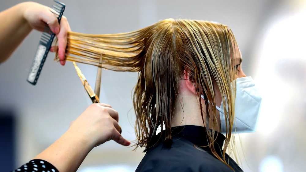 stylist in the process of trimming client's hair with scissors