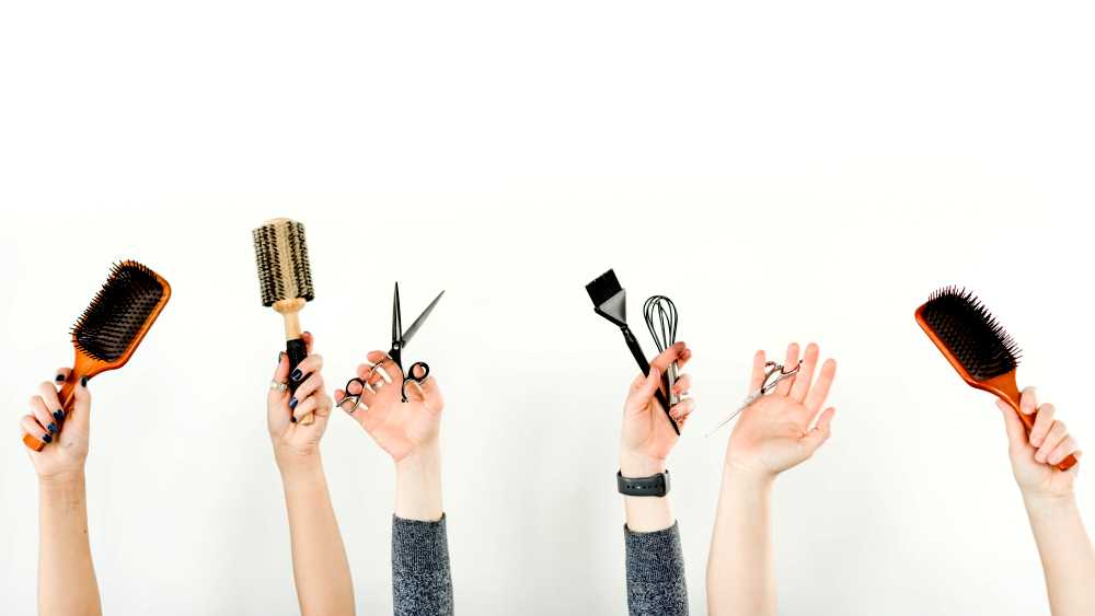 hands raised up holding brushes and scissors